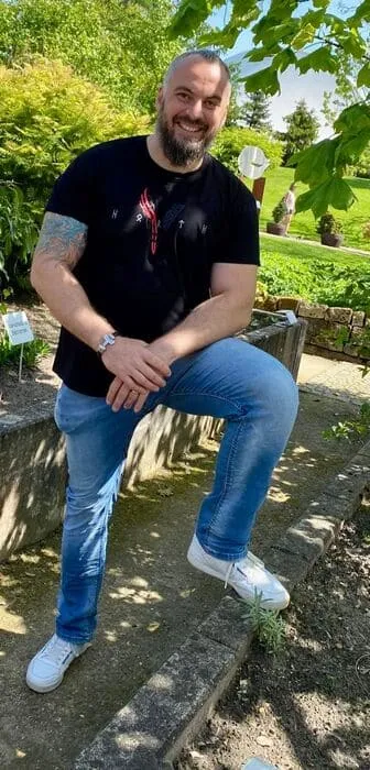 Kunde im Berserker-Shirt steht im Wald und blickt stolz in die Kamera