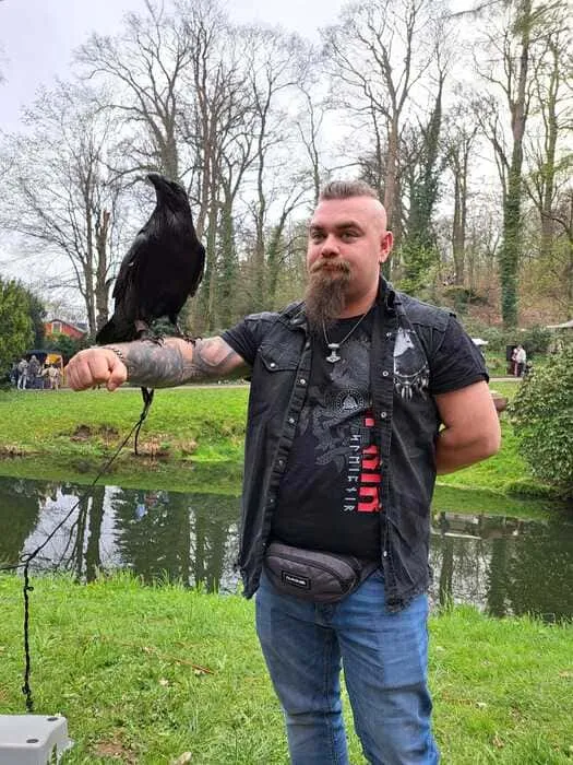 Kunde mit Valhalla-Print-Shirt posiert mit Schwert vor Burgmauer
