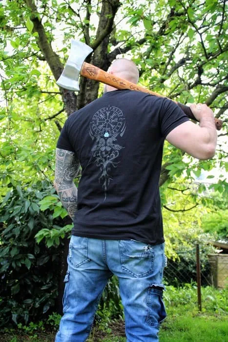 Kunde mit Axt zeigt Rückseite eines Wikinger-Shirts im Grünen