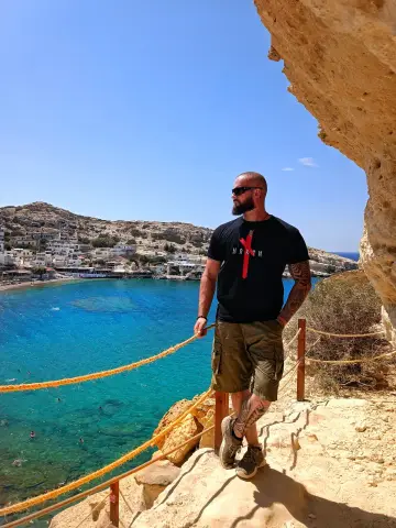 Mann auf einer mediterranen Felsklippe mit blauem Meer im Hintergrund, North Legendary Shirt mit rotem Akzent