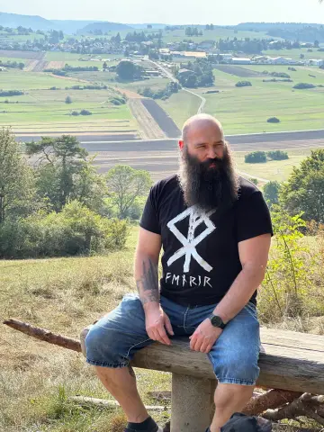 Mann mit langem Bart auf einer Holzbank über einer Bergpanorama, North Legendary Runen-Shirt