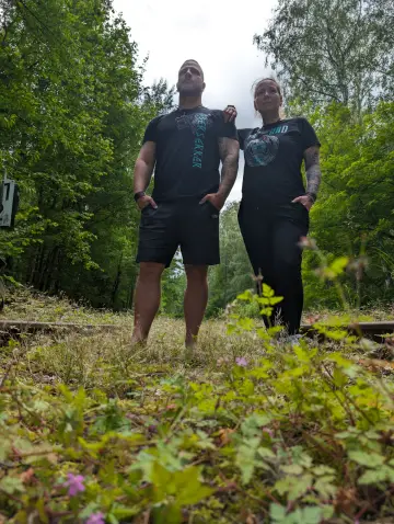 Paar in North Legendary Berserker- und Walhalla-Shirts auf alten Bahngleisen, sommerlicher Wald