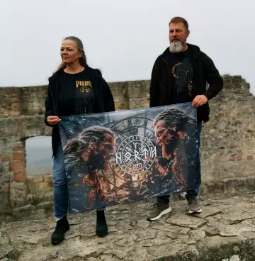Paar präsentiert eine North Legendary Wikinger-Flagge auf der Mauer einer Burgruine im Nebel